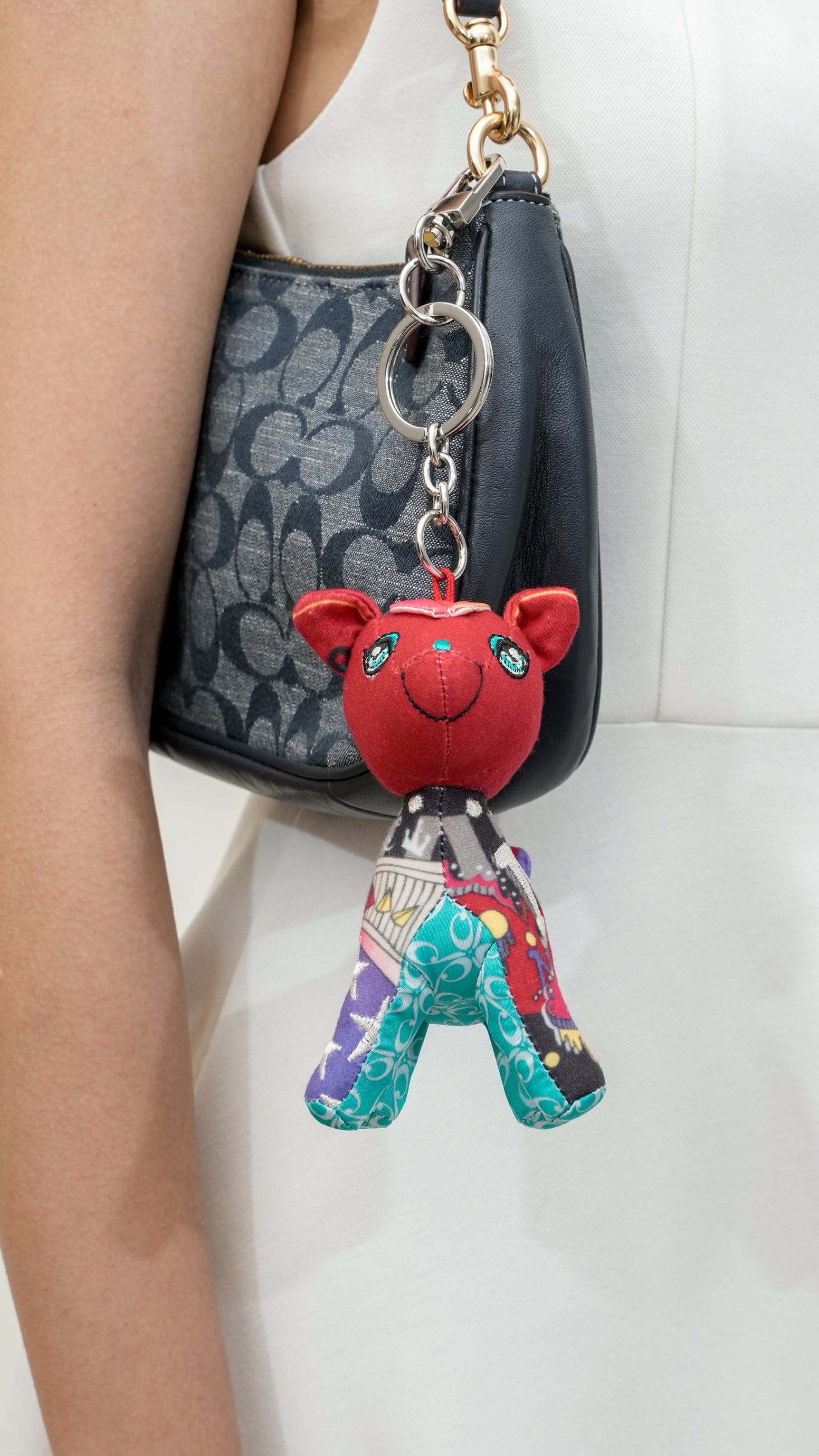 Red deer keychain with colorful pants attached to a black handbag.