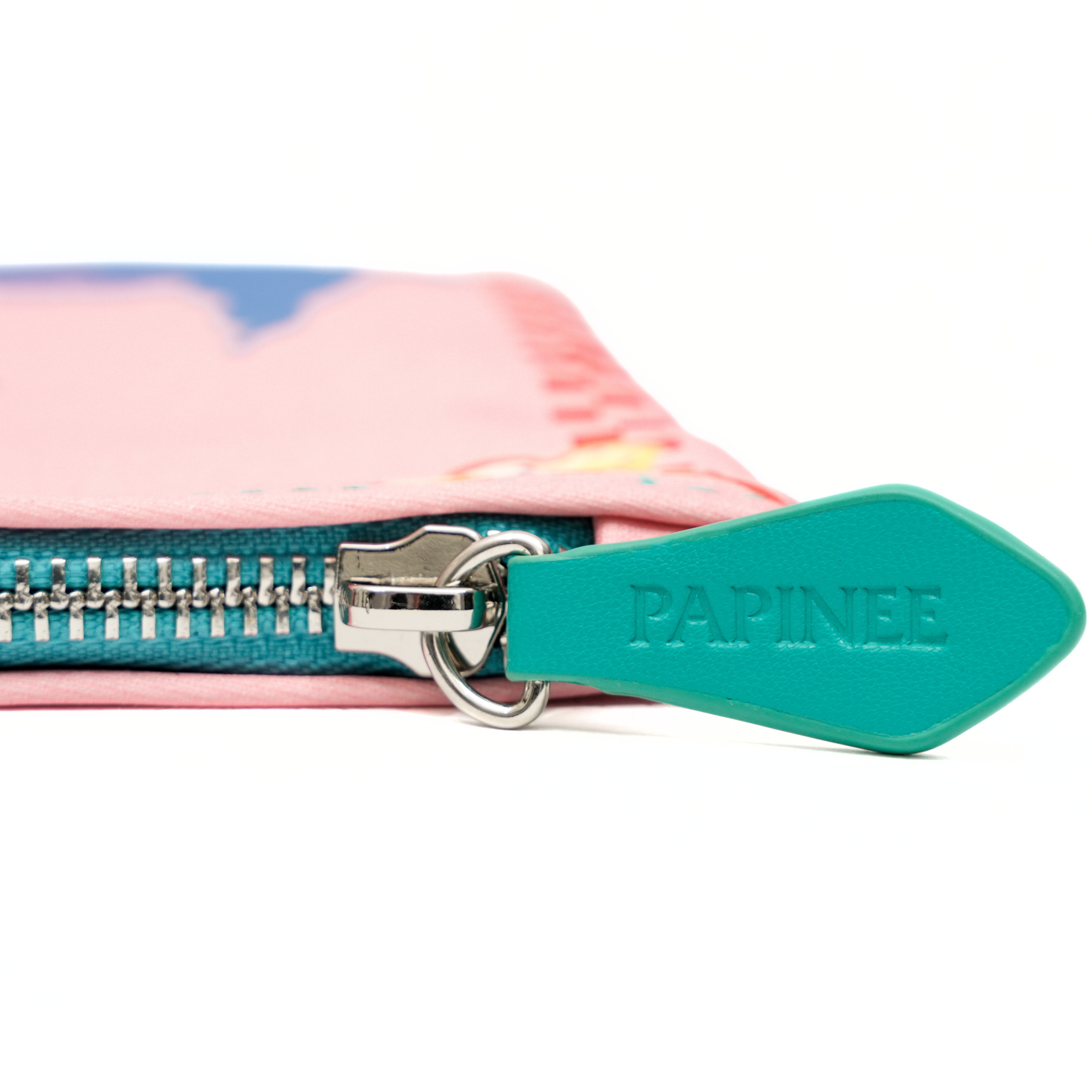 Close-up of a teal zipper with 'PAPINEE' branding on a product with a colorful design.
