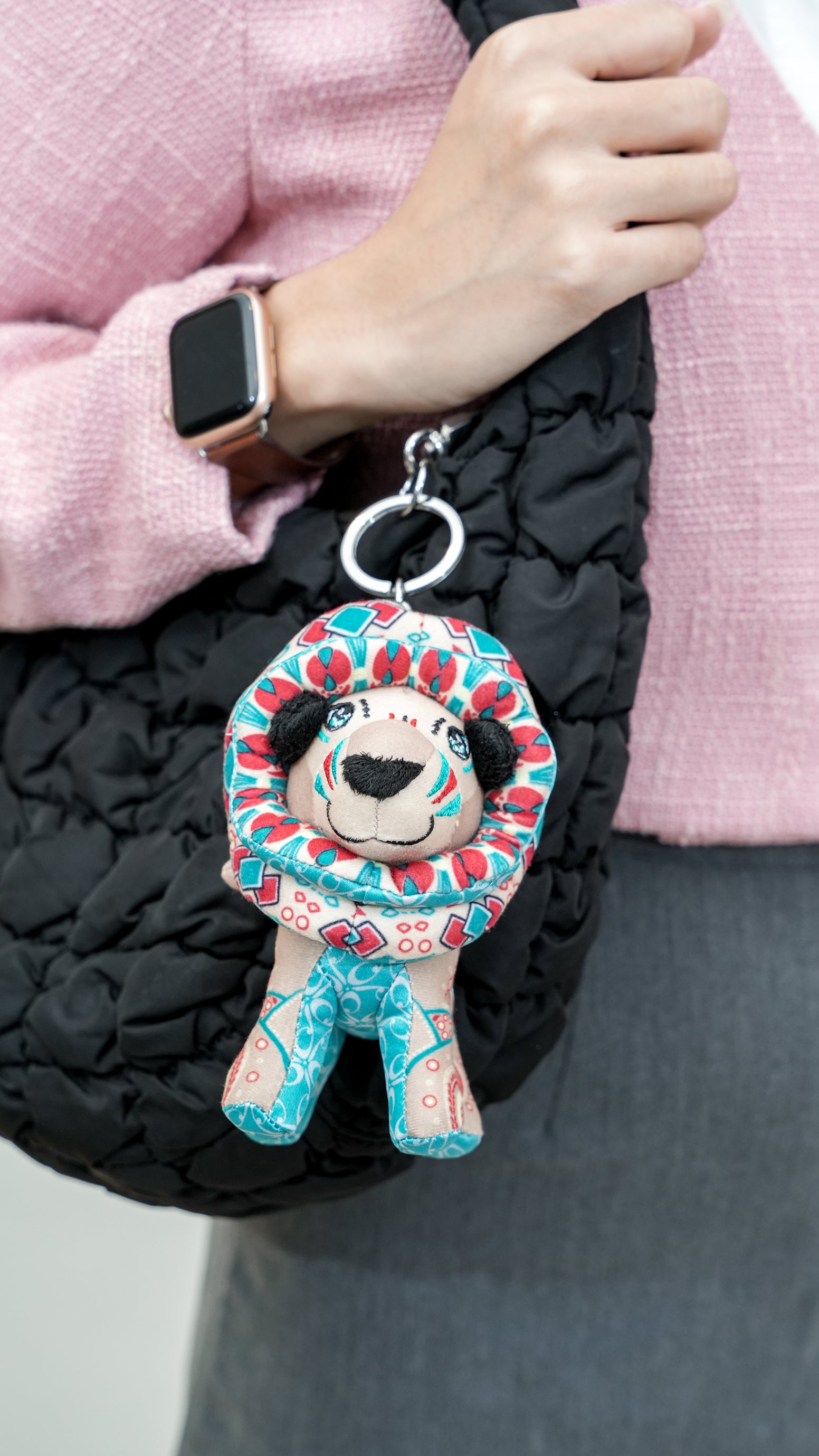Keychain with a lion design held by a person wearing a pink jacket.
