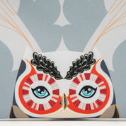 Close-up of a decorative pillow with an owl design on a patterned background