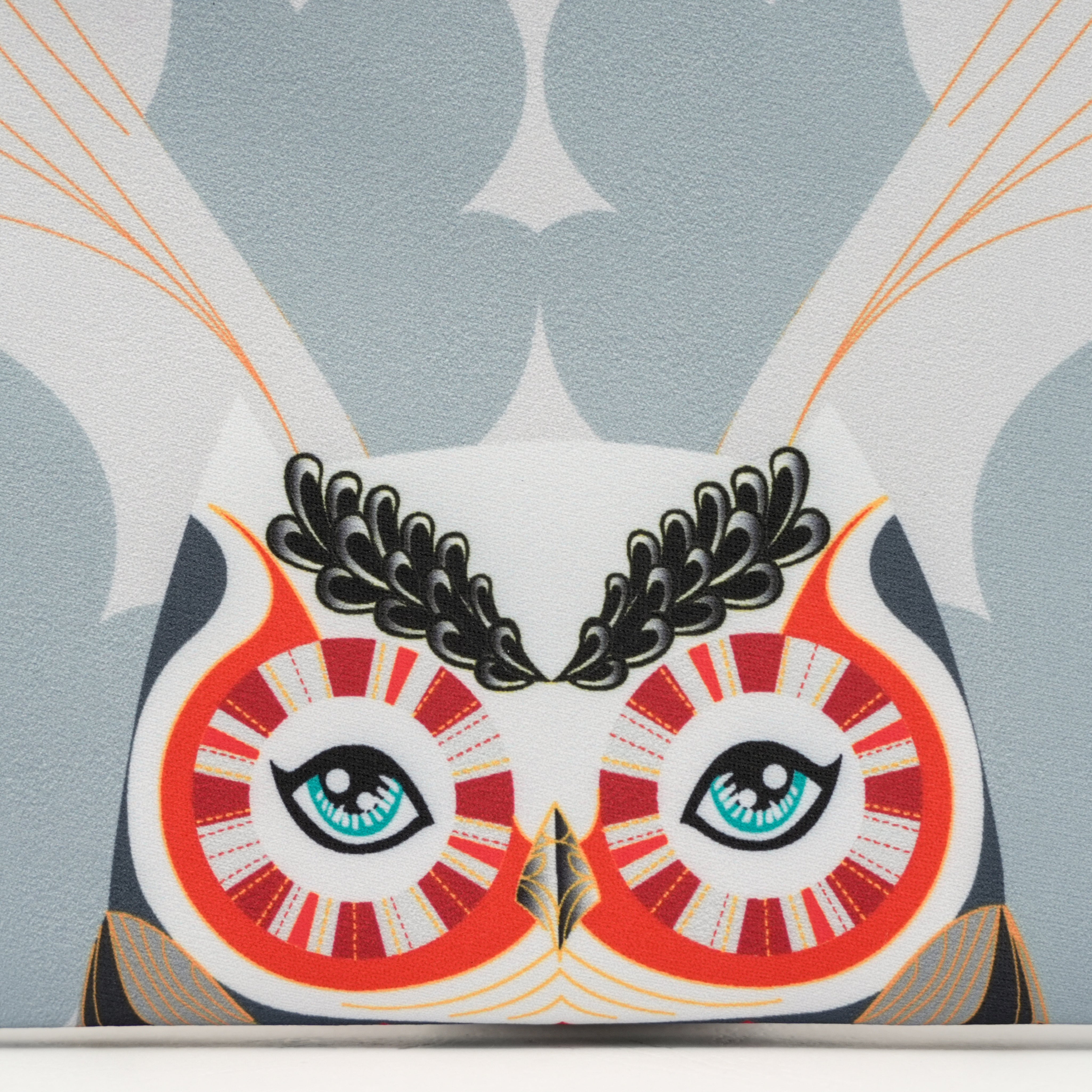 Close-up of a decorative pillow with an owl design on a patterned background