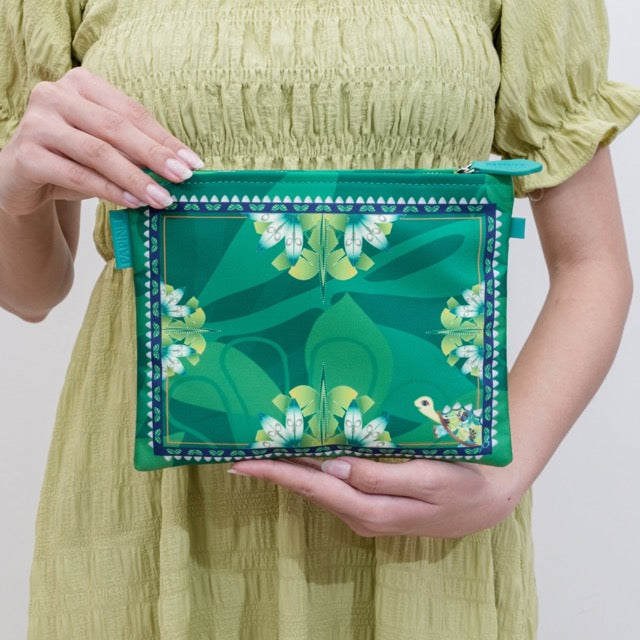 Person holding a green clutch with floral design against a plain background
