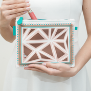 Person holding a geometric-patterned pouch with a lip tint inside on a white background
