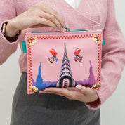 Person holding a pink pouch with cartoon characters and landmarks on a white background