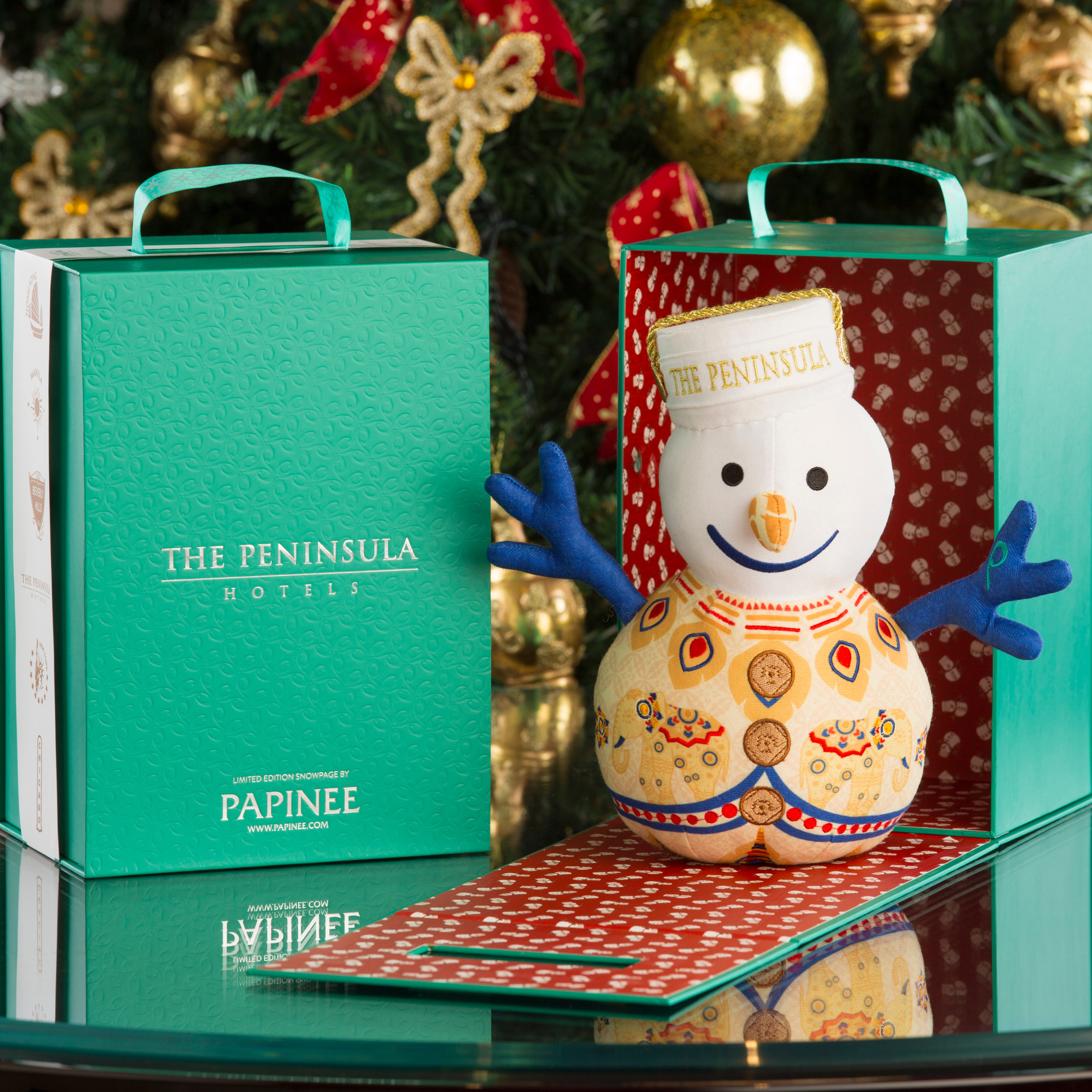 Decorative snowman figurine with 'The Peninsula' branding next to a green box.